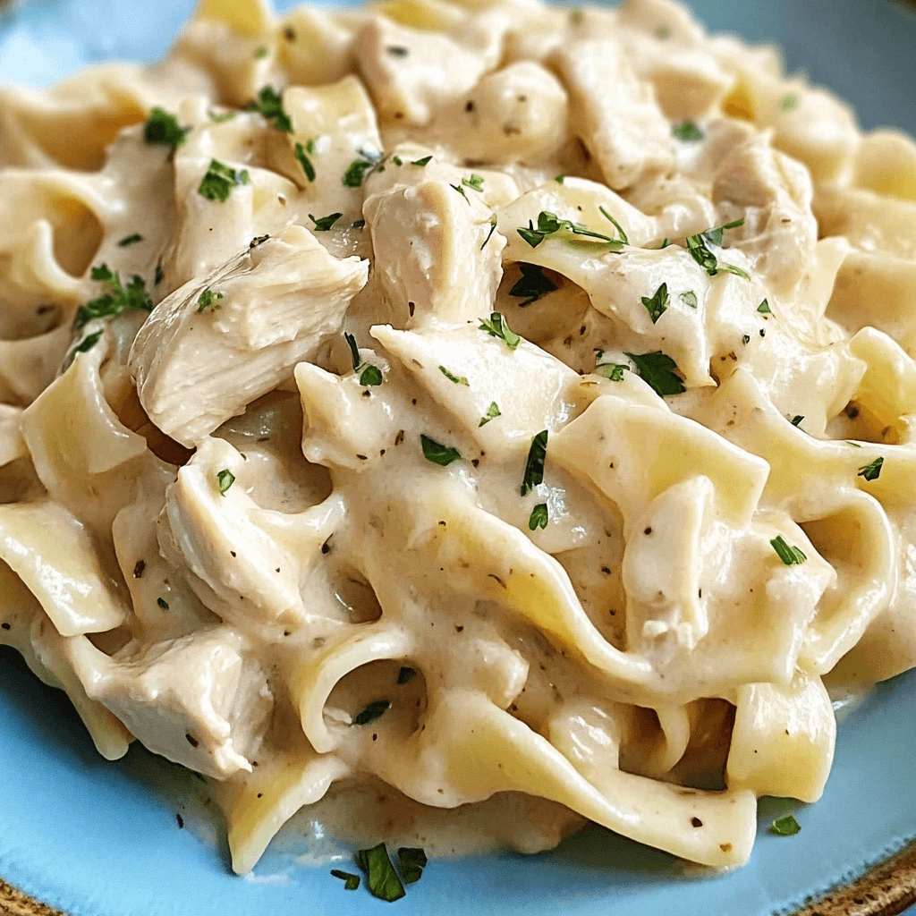 A bowl of creamy chicken noodle pasta with herbs.