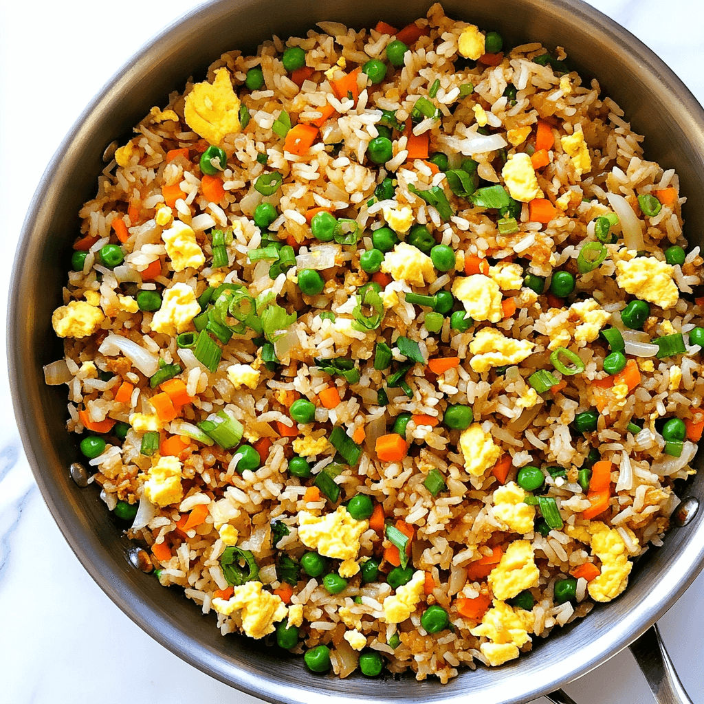 A vibrant and colorful fried rice dish with golden rice, tender vegetables, and perfectly cooked eggs, served in a silver wok, ready to be enjoyed.