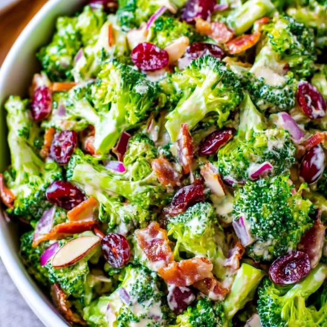 A bowl of fresh broccoli salad with colorful vegetables and dressing.