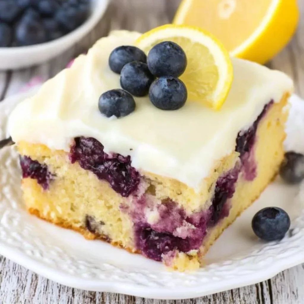 Lemon blueberry cake with fresh blueberries and lemon zest on a serving plate