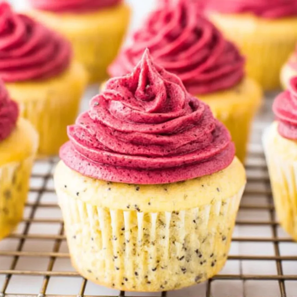 Lemon poppy seed cupcakes with blackberry frosting on a wooden table