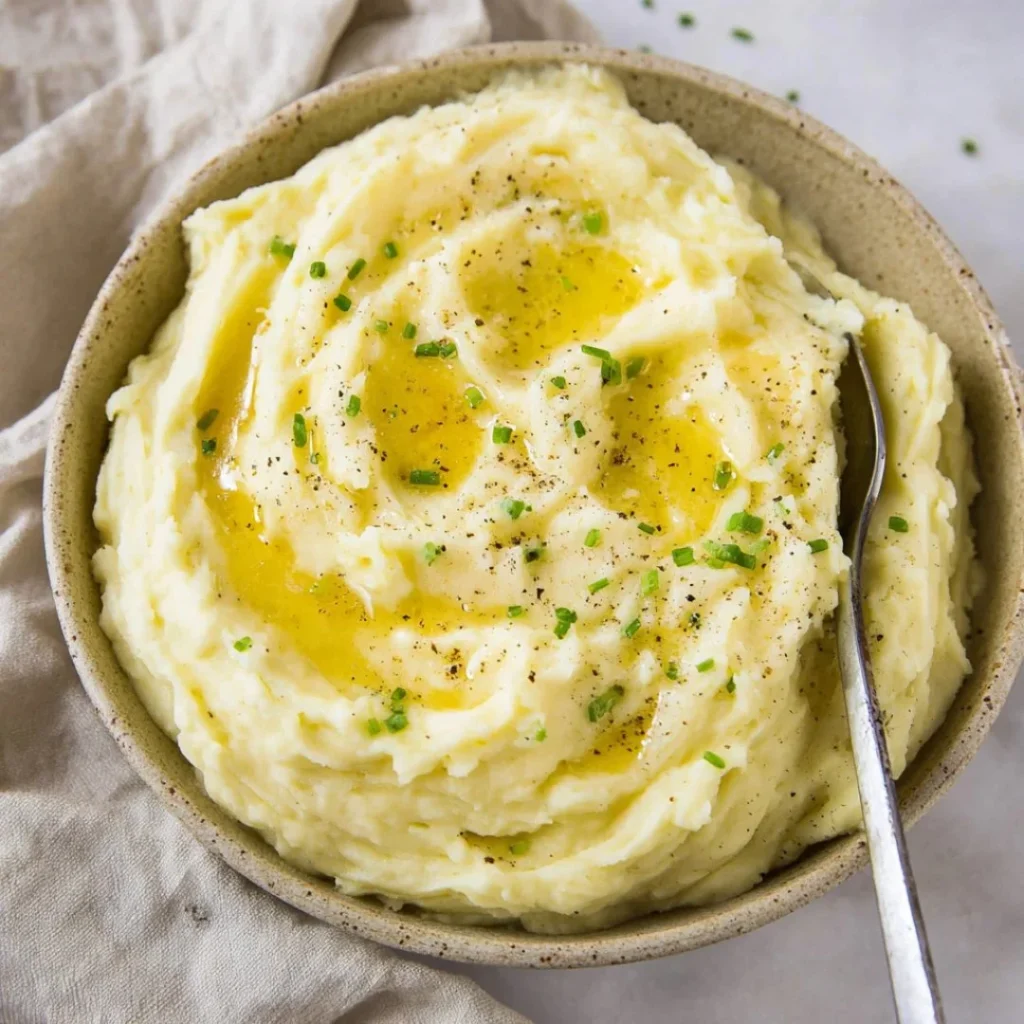 Creamy mashed potatoes served in a bowl, garnished with fresh herbs.