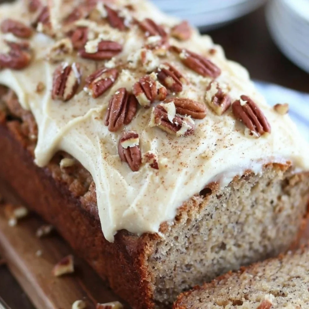 Delicious banana bread cake with cream cheese frosting on a white plate