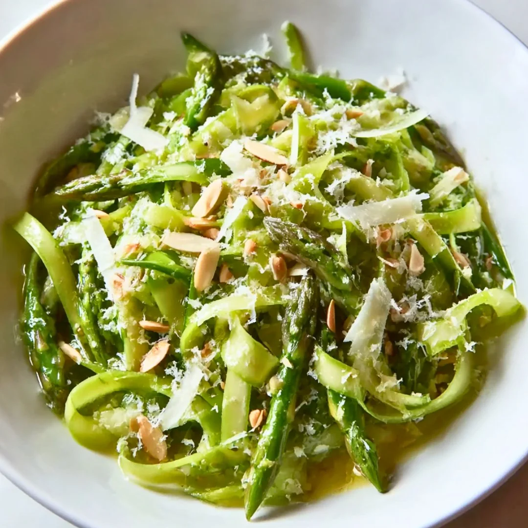 Shaved asparagus salad with lemon dressing on a plate, garnished with herbs.