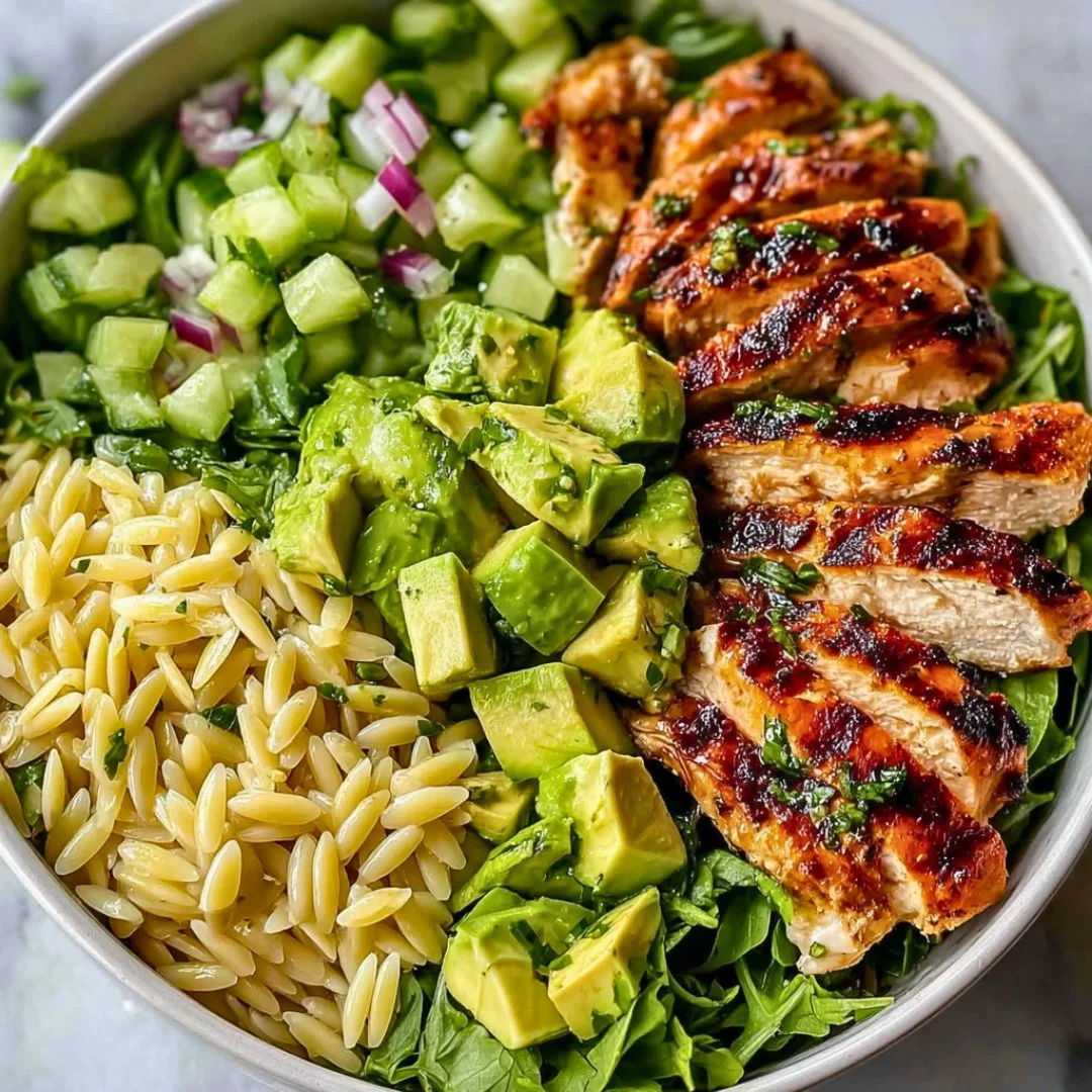 Delicious Grilled Chicken Orzo Salad garnished with fresh vegetables and herbs.