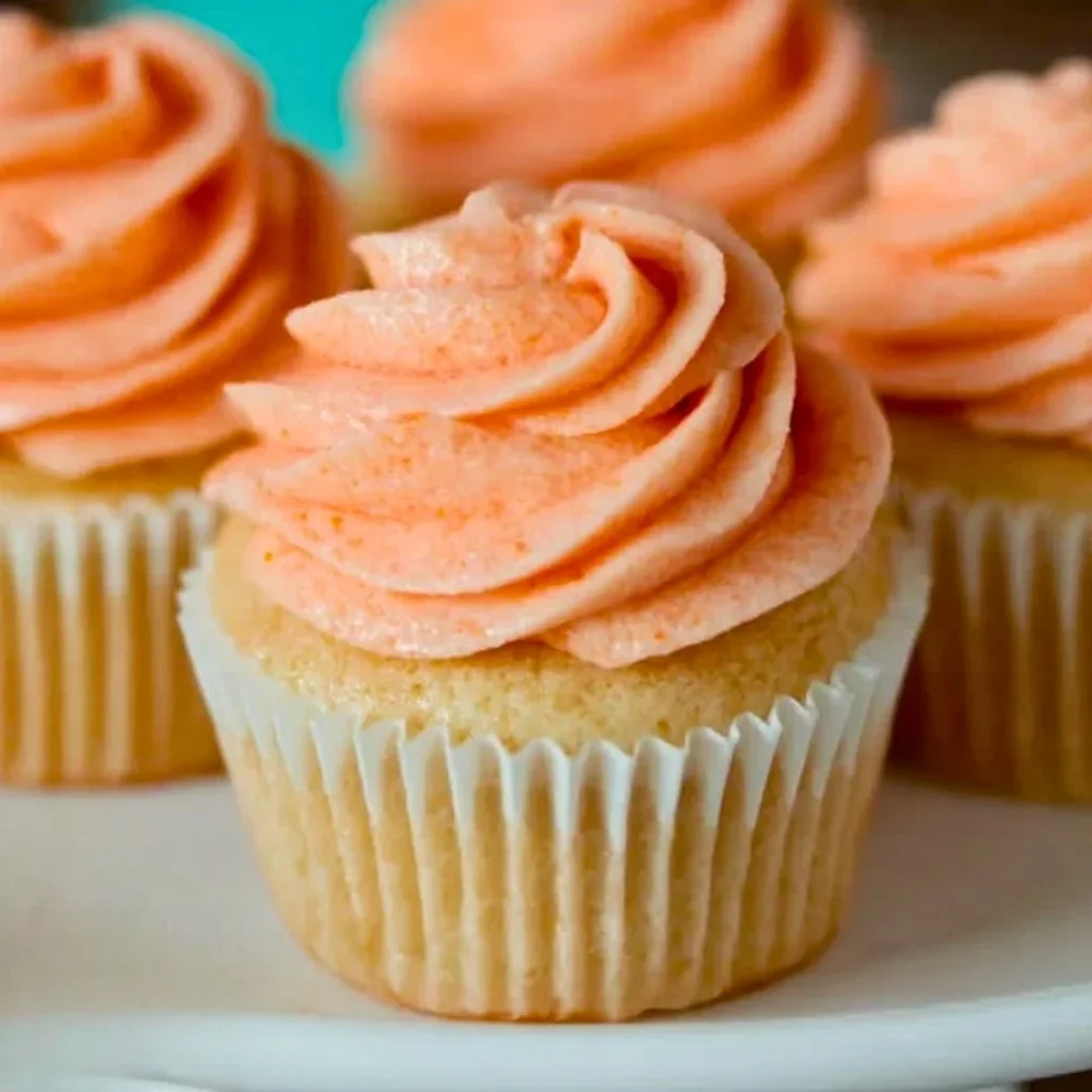 Delicious Peaches & Cream Cupcakes topped with peach slices and whipped cream.