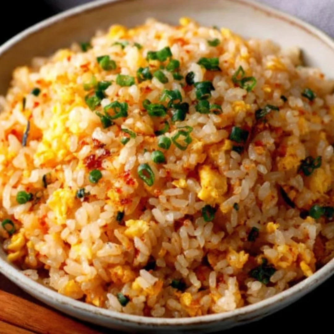Plate of savory Japanese garlic fried rice garnished with green onions and served in a bowl.