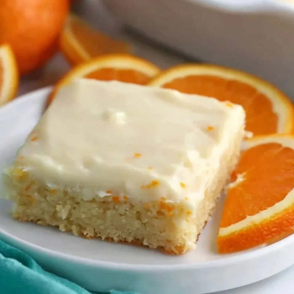 Delicious Orange Brownies topped with a citrus glaze on a rustic wooden table