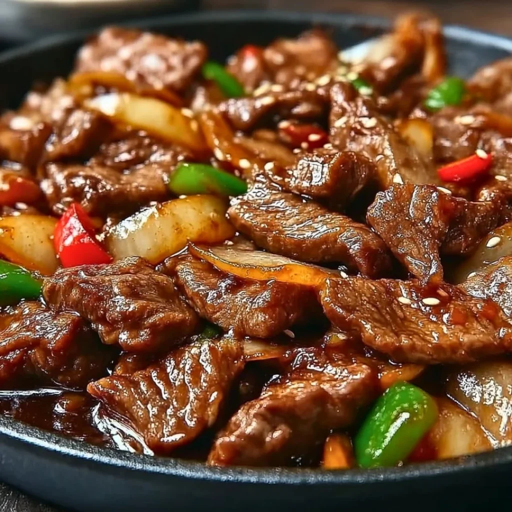 Sizzling Chinese pepper steak with onions on a plate, garnished and ready to serve.