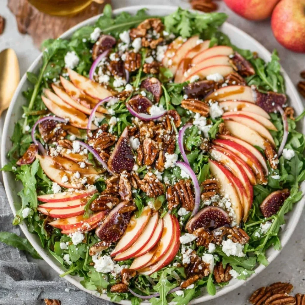 Delicious Apple Arugula Salad topped with Maple Pecans on a wooden table