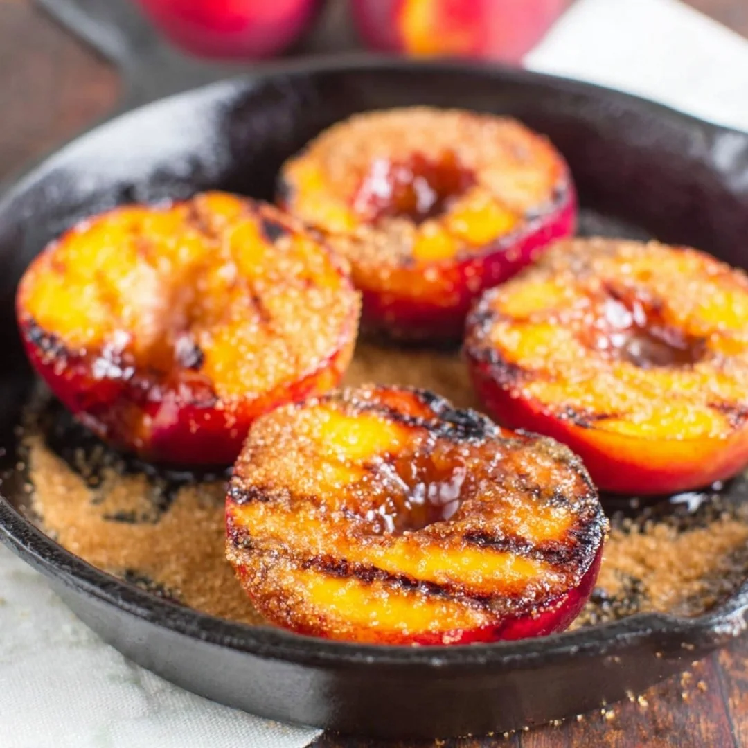 Delicious grilled peaches topped with cinnamon and brown sugar on a plate.