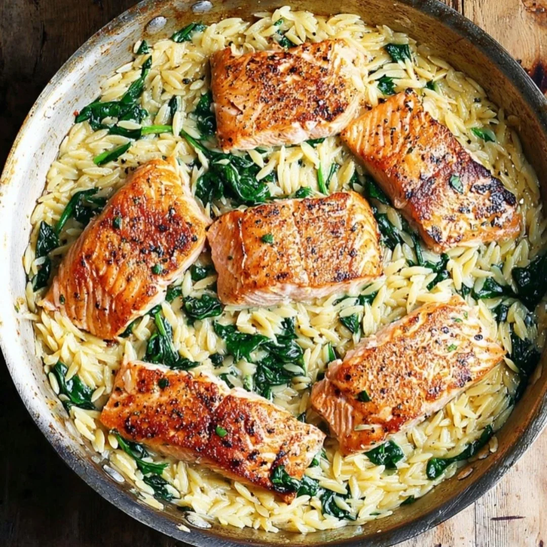 One skillet salmon with lemon orzo garnished with herbs on a white plate