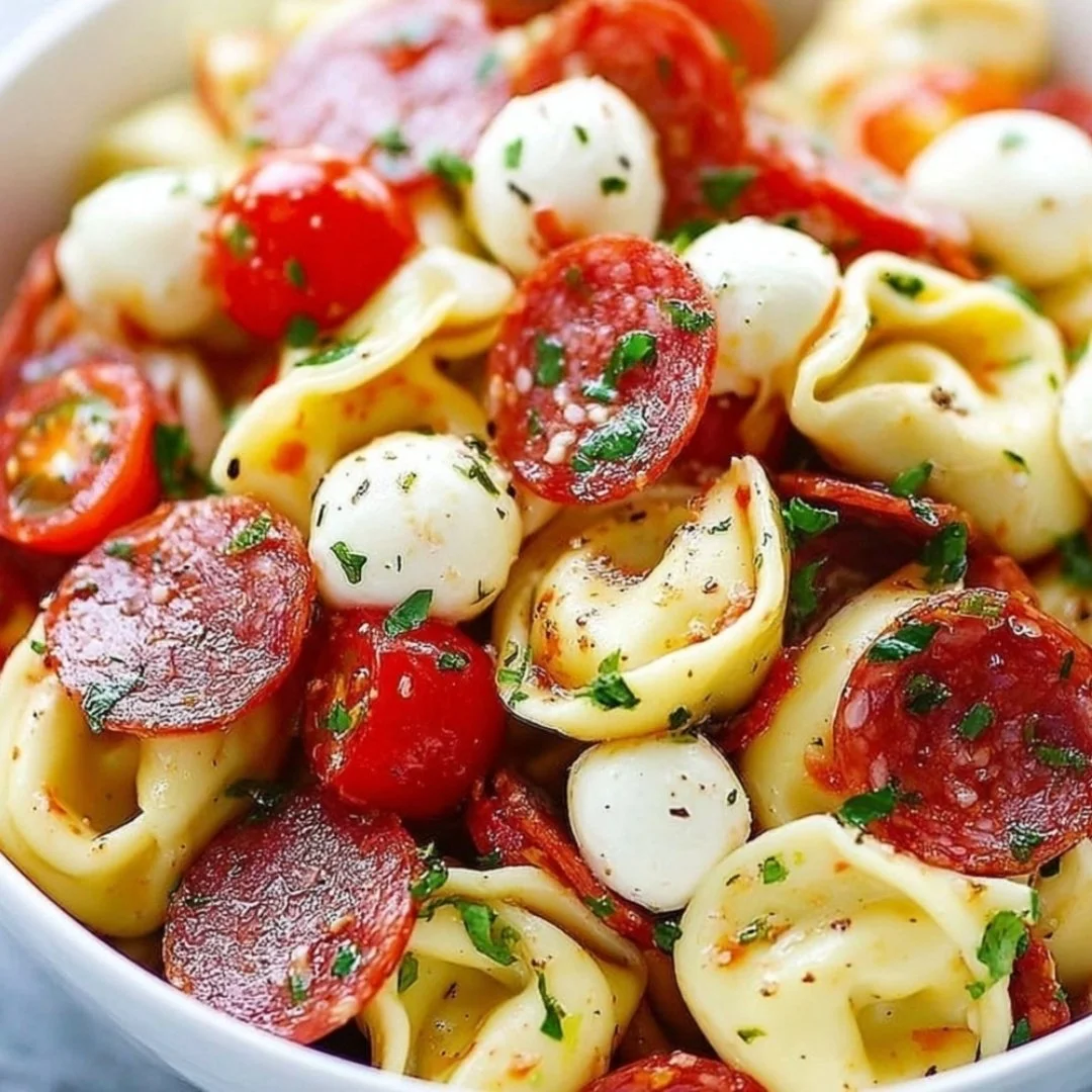 A vibrant roasted red pepper and parmesan tortellini salad in a bowl.