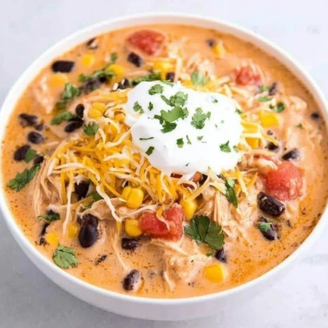 Bowl of slow cooker chicken enchilada soup topped with cheese and cilantro