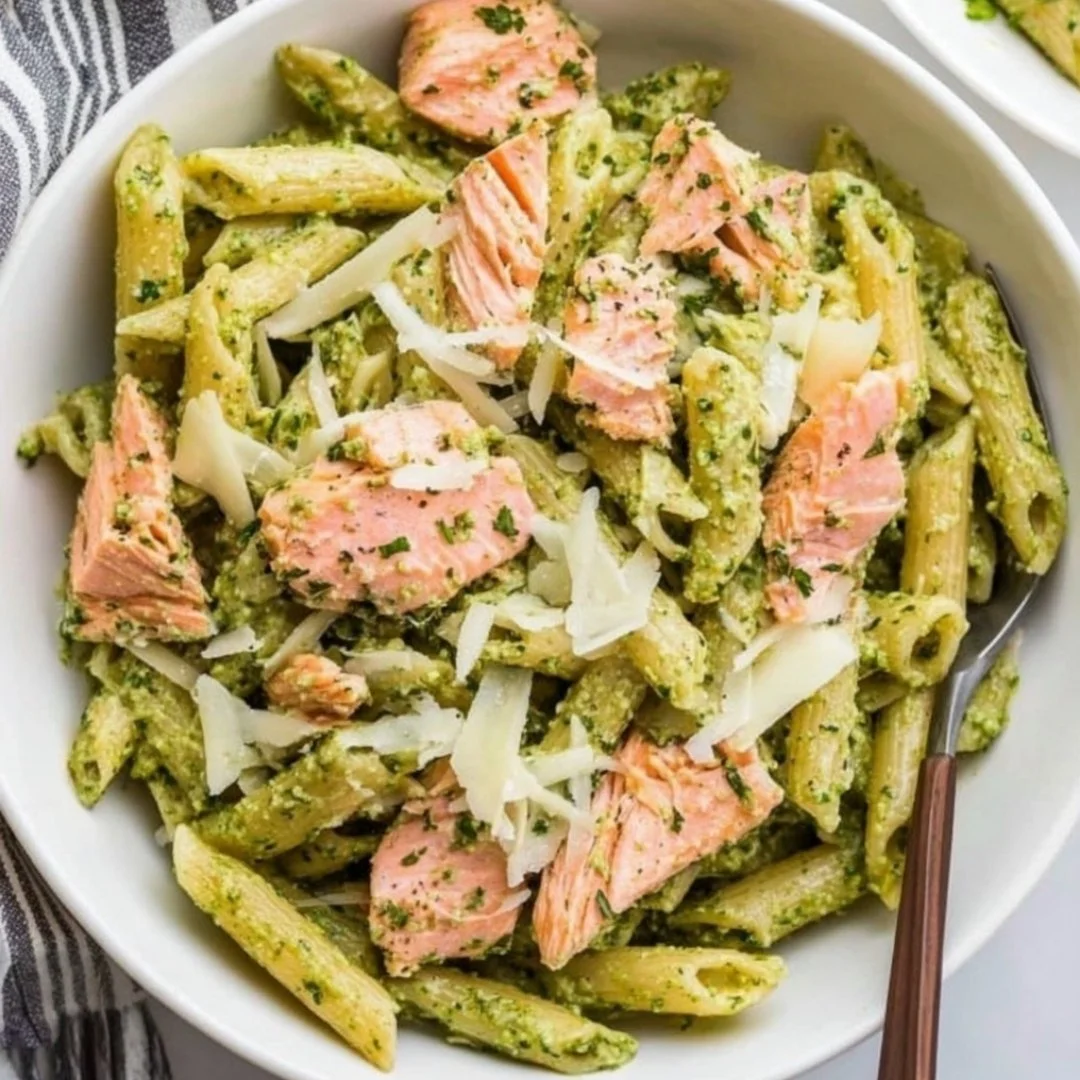 Delicious salmon pesto pasta served in a bowl, garnished with basil.