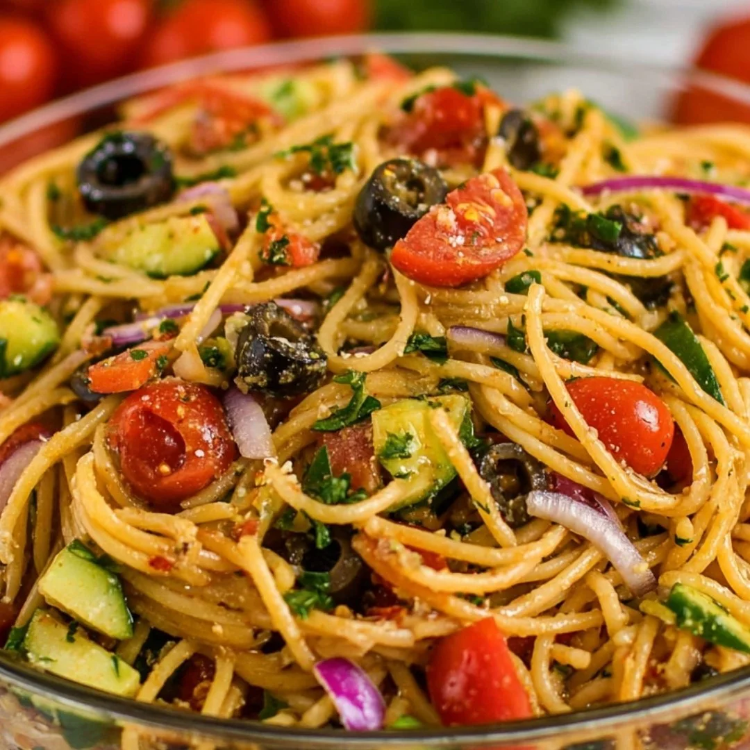 Colorful bowl of spaghetti salad with fresh vegetables and dressing