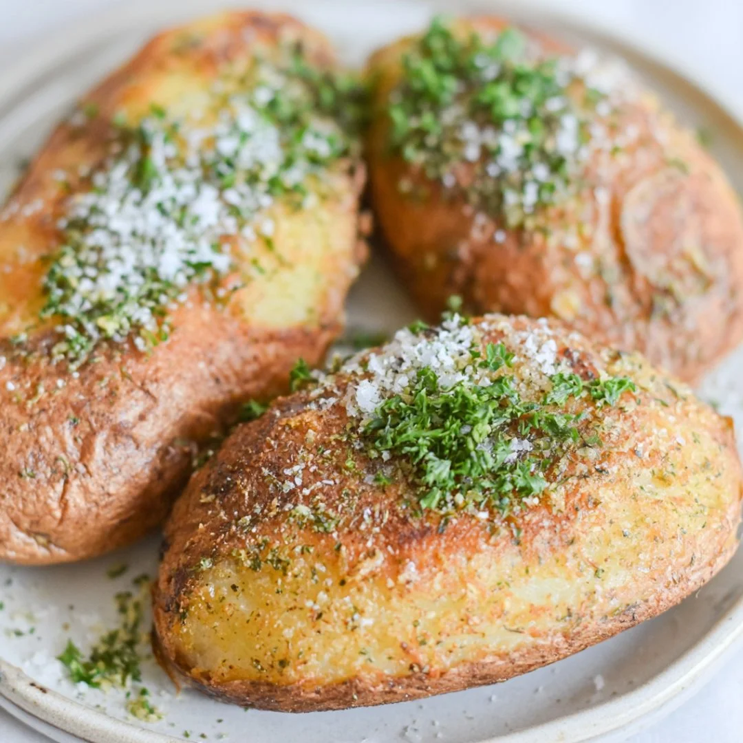 Crispy air fryer baked potatoes topped with butter and herbs