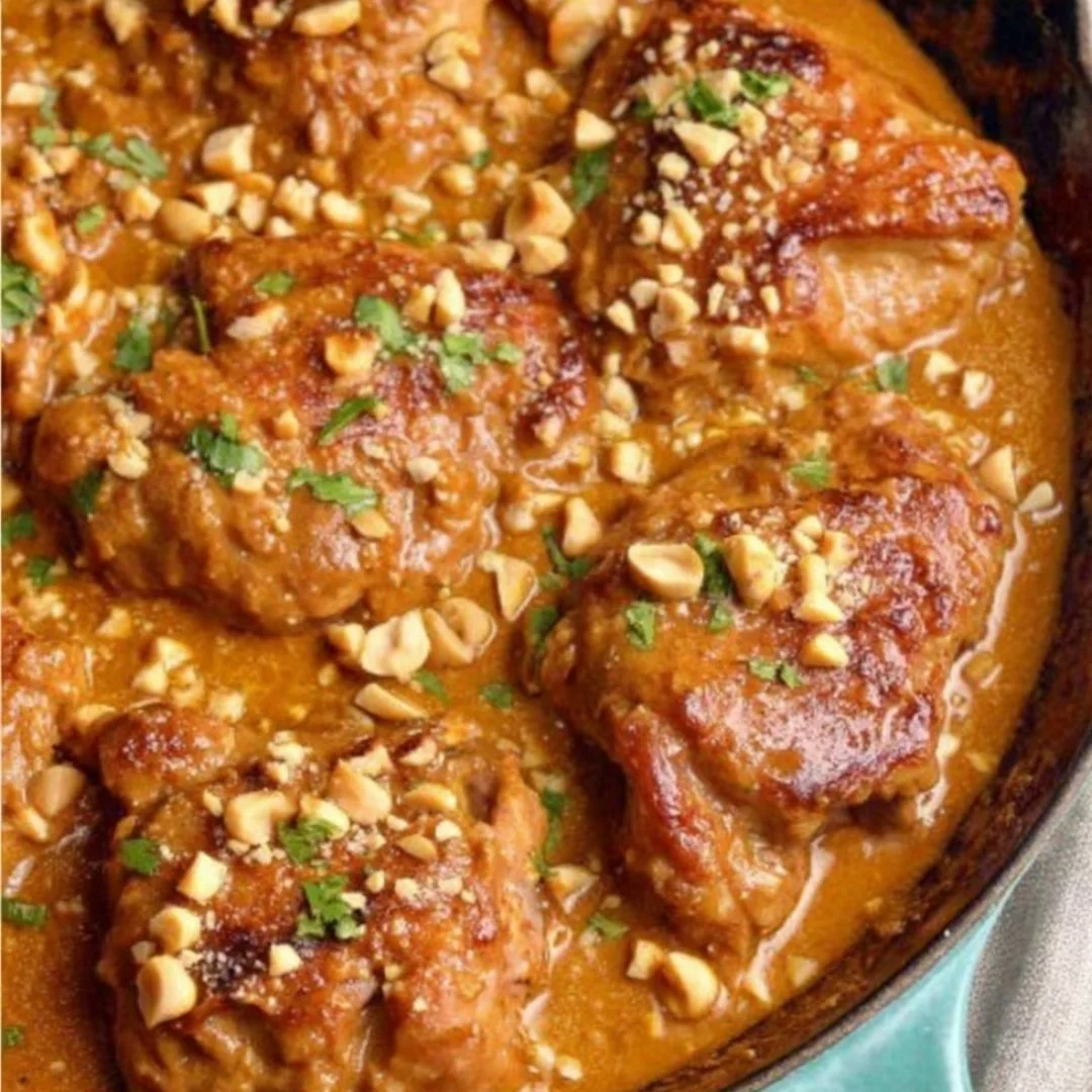 Baked Thai Peanut Chicken Thighs garnished with peanuts and herbs.