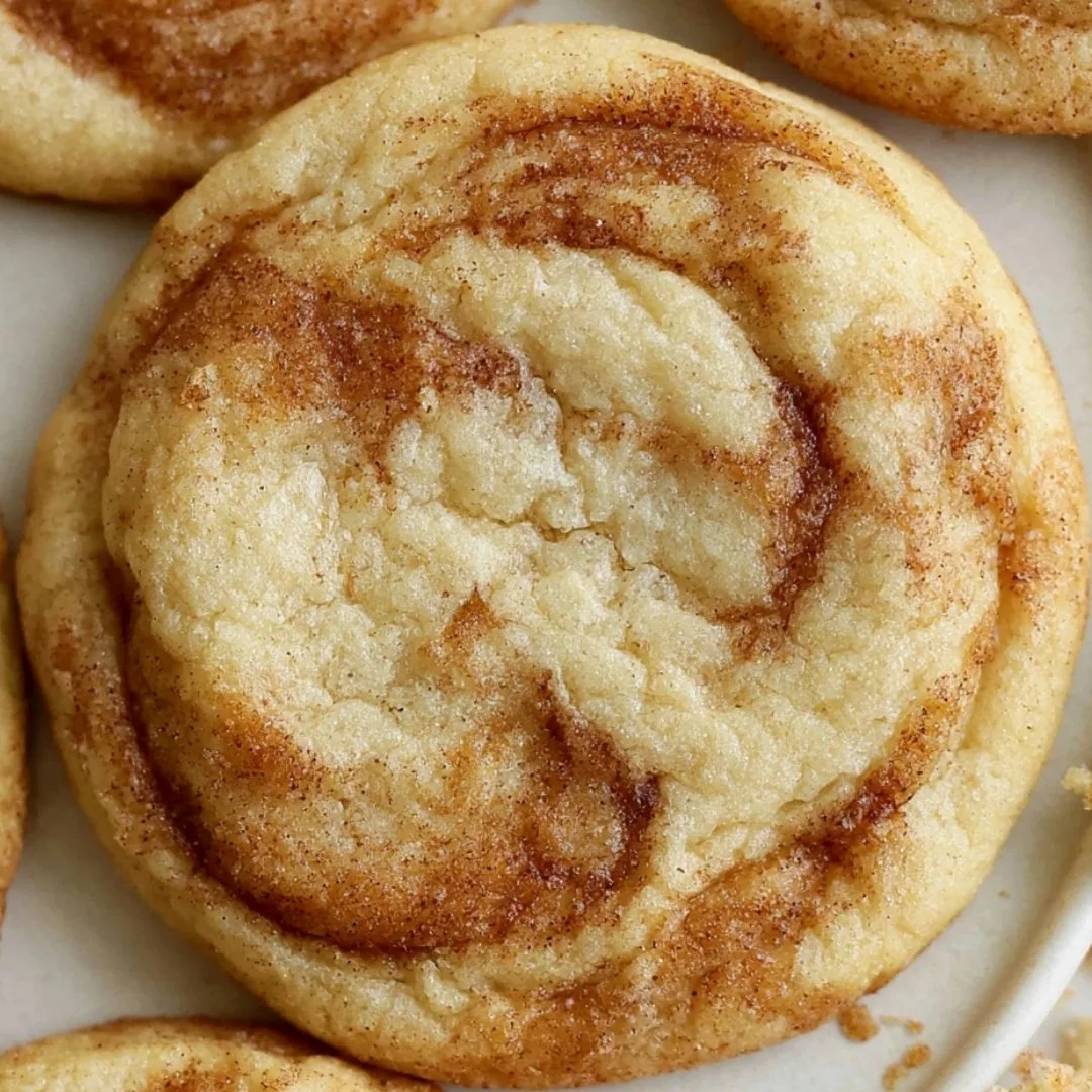 Freshly baked cinnamon swirl cookies stacked on a plate.