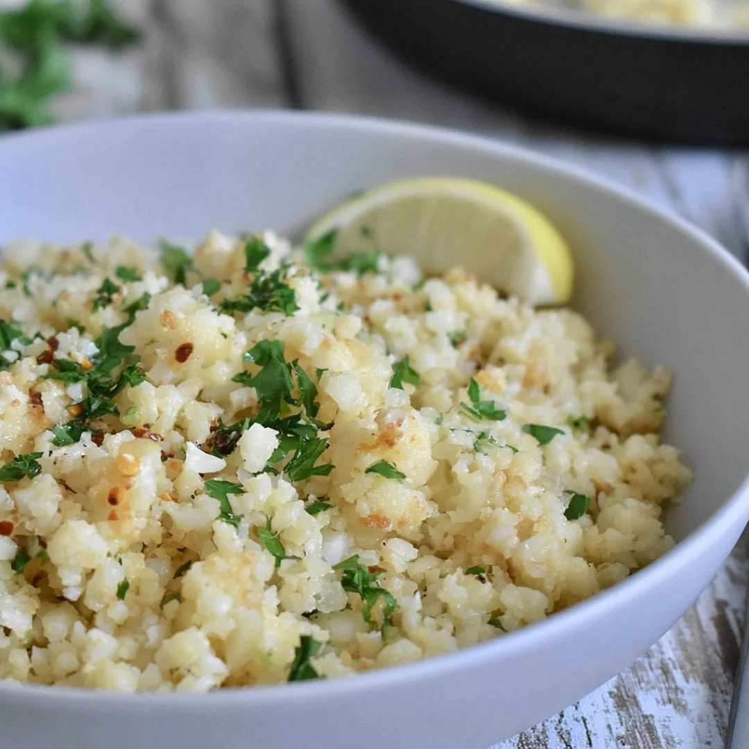 Delicious Garlic Butter Cauliflower Rice served in a bowl with herbs.