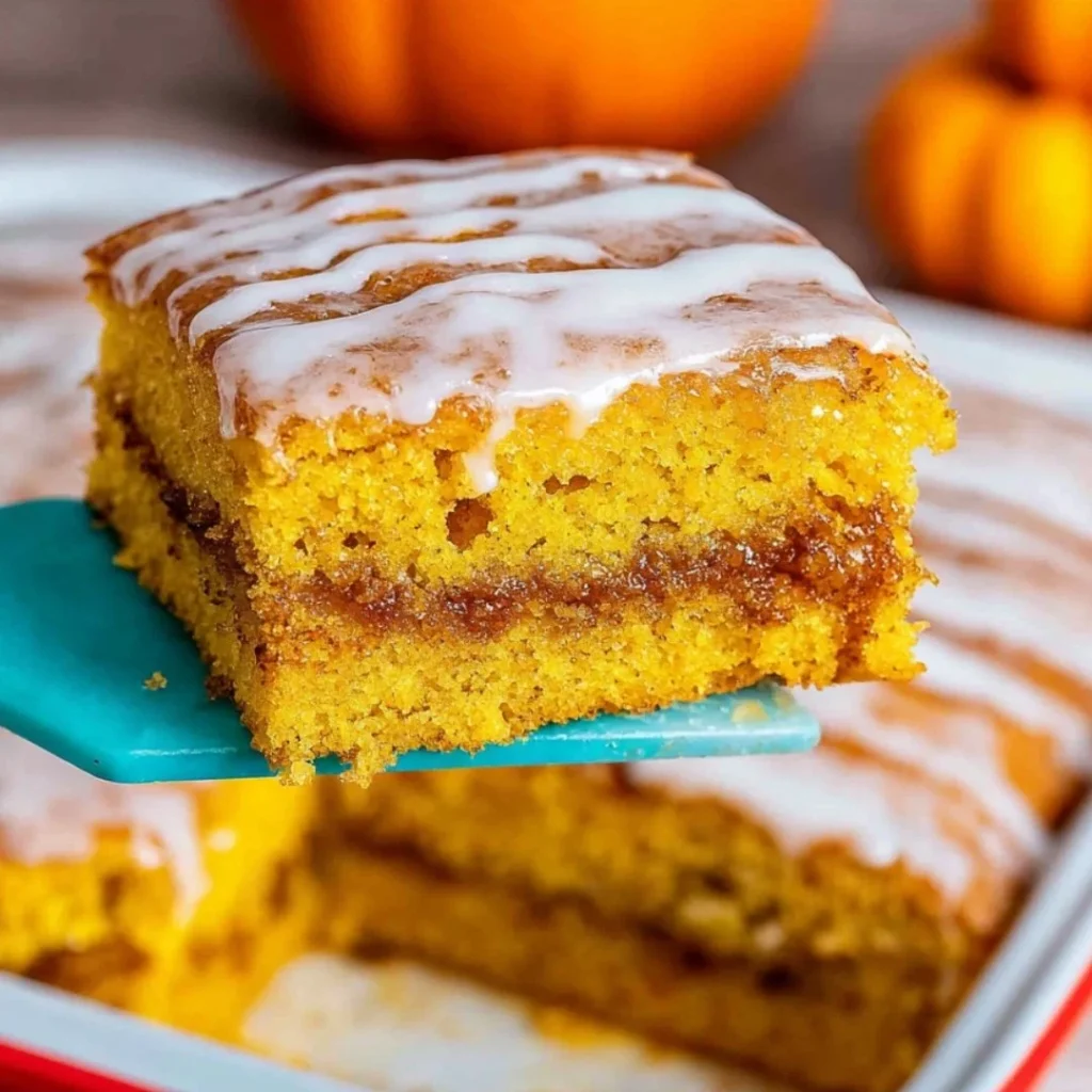Slice of Pumpkin Honey Bun Cake topped with glaze and spices on a rustic table